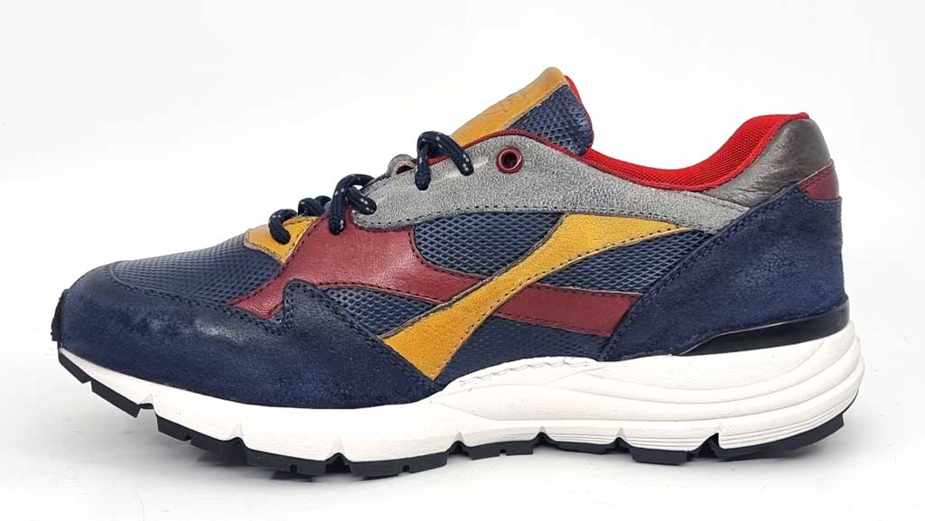 A shot of the internal side of the sneaker, featuring the same vibrant color details. The yellow, grey, and red accents stand out against the deep blue leather. The soft leather lining is subtly visible, hinting at the luxurious comfort inside. The shoe's streamlined silhouette is perfect for both casual and smart-casual outfits.